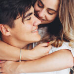 девушка обнимает парня со спины и смеется